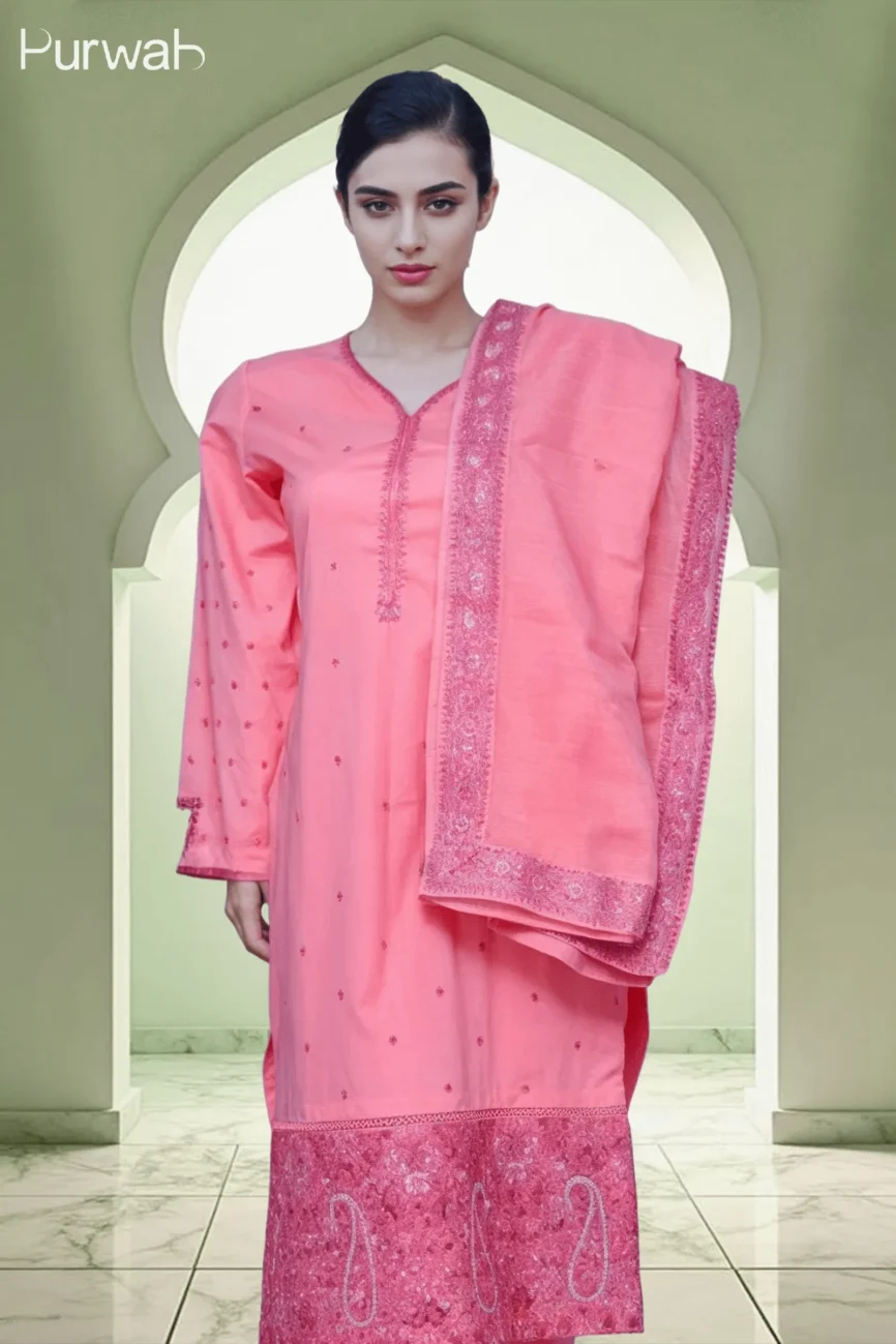 A woman in a pink embroidered kurta with a matching dupatta, standing in front of an archway, showcasing the delicate floral design and elegant details of the outfit.