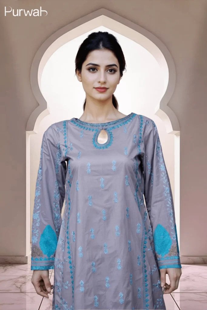 Model wearing a grey dress with turquoise floral embroidery, featuring a keyhole neckline and a minimalistic design, with a neutral background.