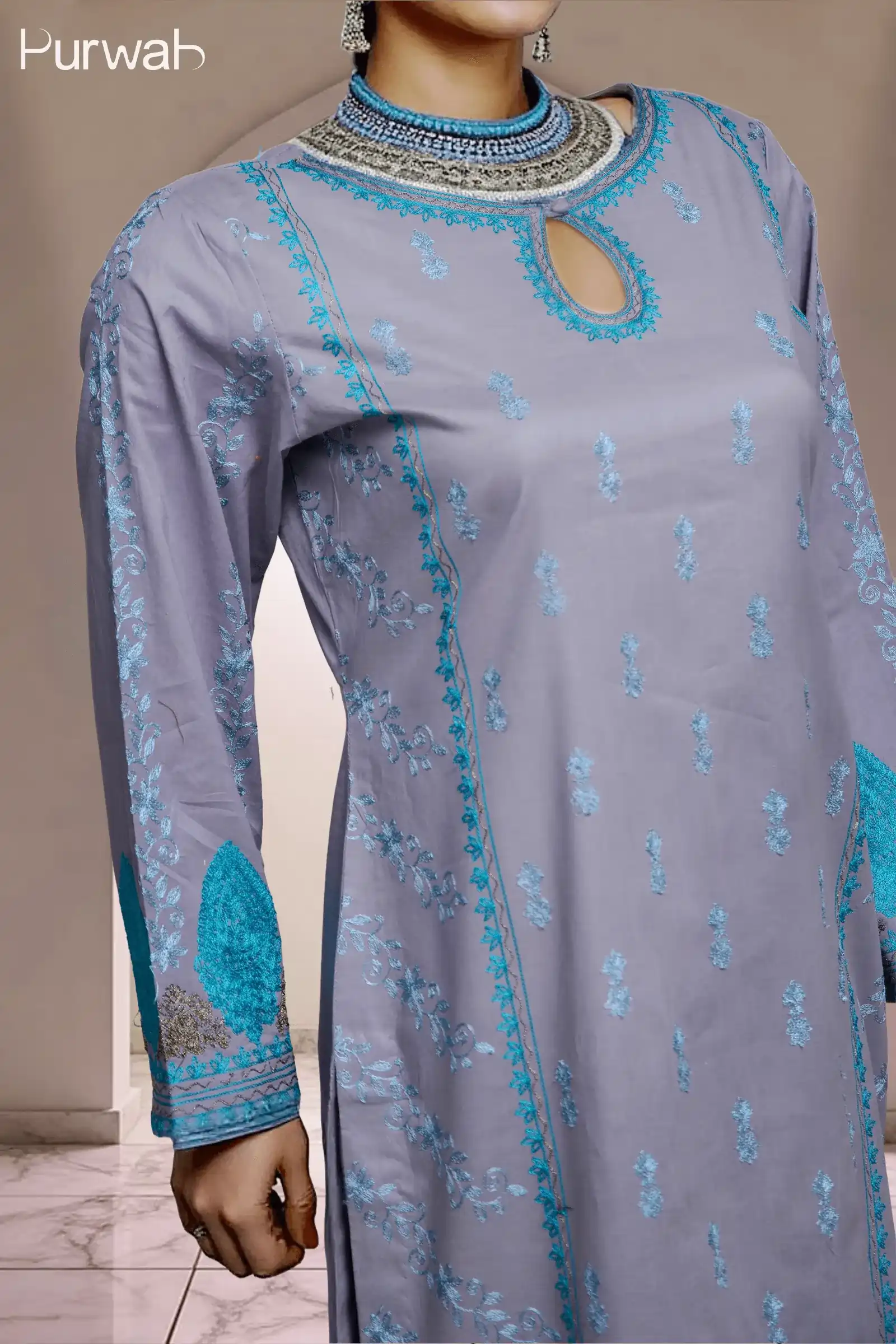 Side view of the model wearing a grey dress with turquoise floral embroidery, highlighting the detailed neckline and embroidery, paired with a necklace.